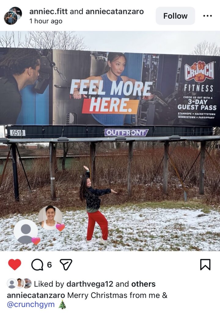 highway billboard with Crunch gym trainer standing in front of it