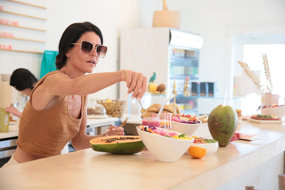woman adds fork to white salad bowl prepared for guests