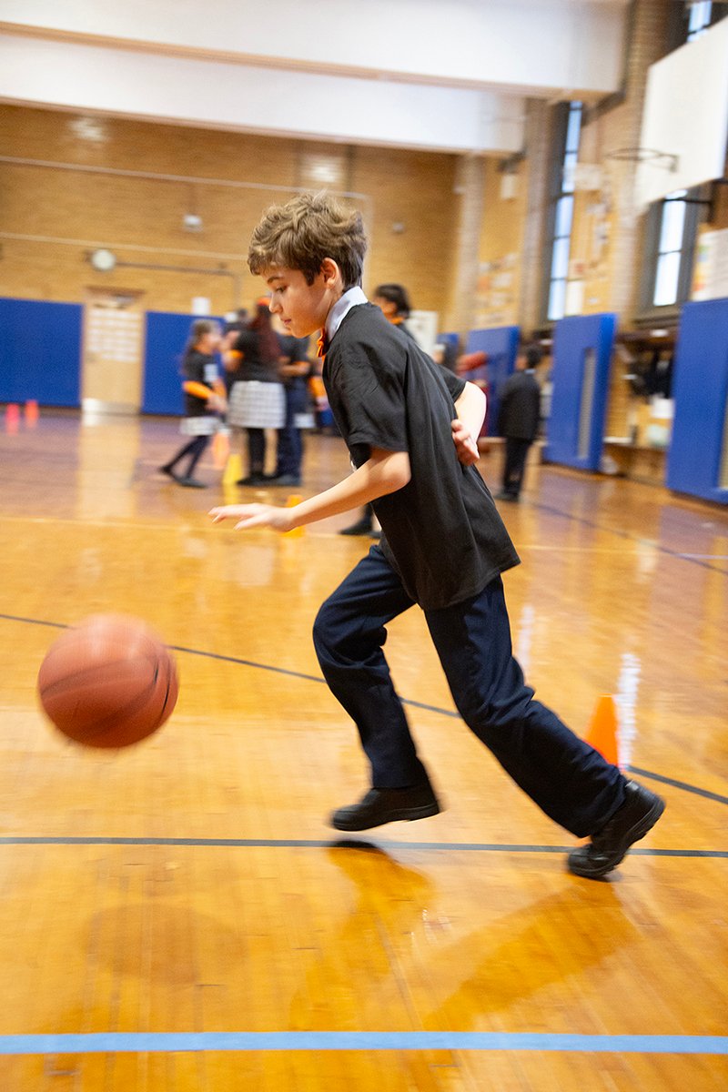 boy dribbles ball with one arm behind his back