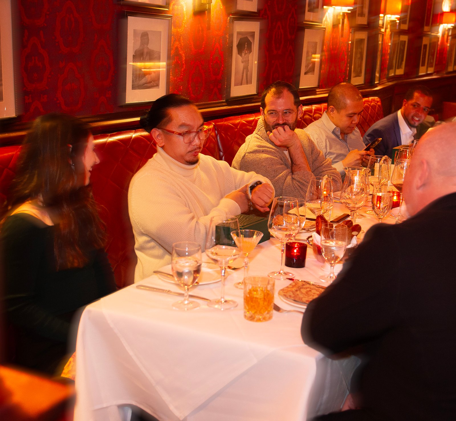 man checks his watch for the amusement of other diners at his table