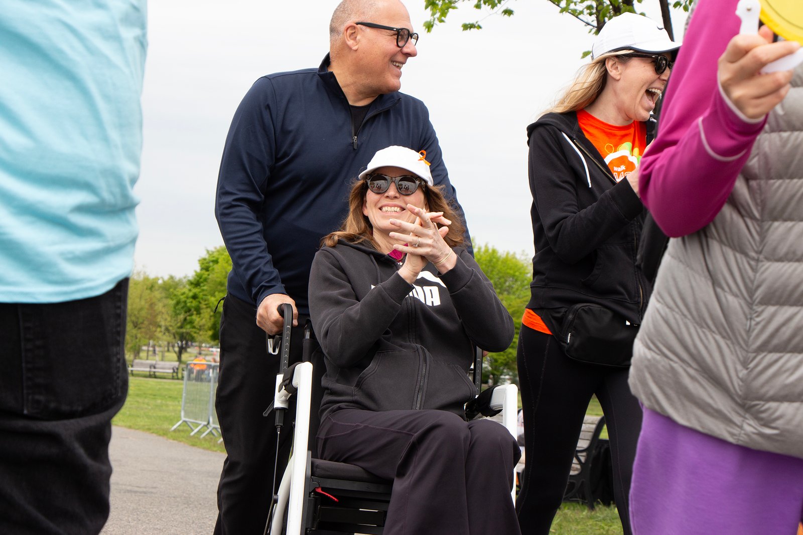 woman in wheelchair claps her hands as she crosses the finish line
