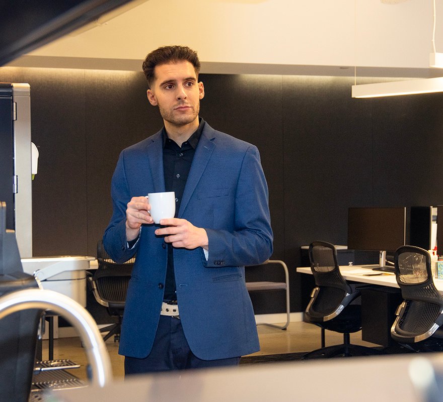 man holds white coffee cup in office setting