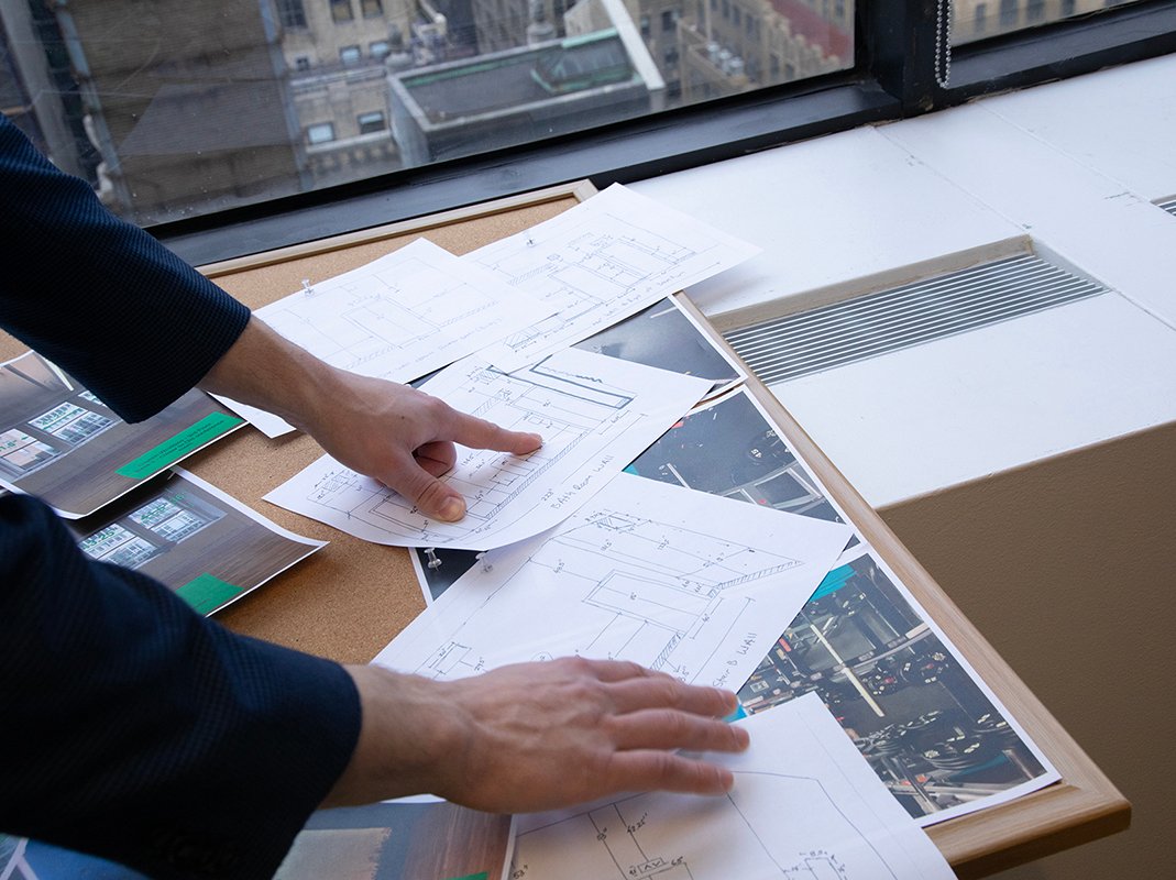man's hands point to floorplans and inspiration pinned to bulletin board
