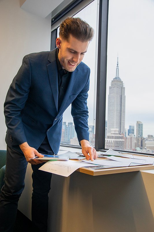 man leans over bulletin board full of papers